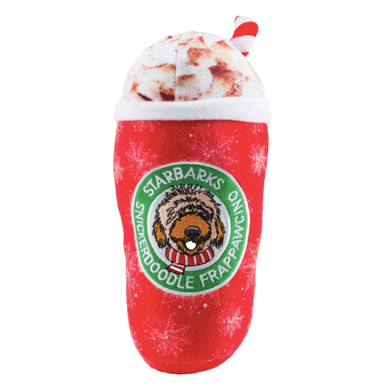 A plush dog chew toy shaped like a tall, red snowflake covered coffee cup and whipped cream and candy striped straw with circular dog logo in middle of cup with white embroidered writing reading, "Starbarks Snickerdoodle Frappawcino". Photographed on white background