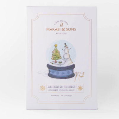A rectangular white paper packaging with design in middle of snowglobe containing snowman and christmas tree. text on package reads, "Makabi & Sons Happy Holidays With Love Noel Shortbread Butter Cookies". Photographed on white background. 