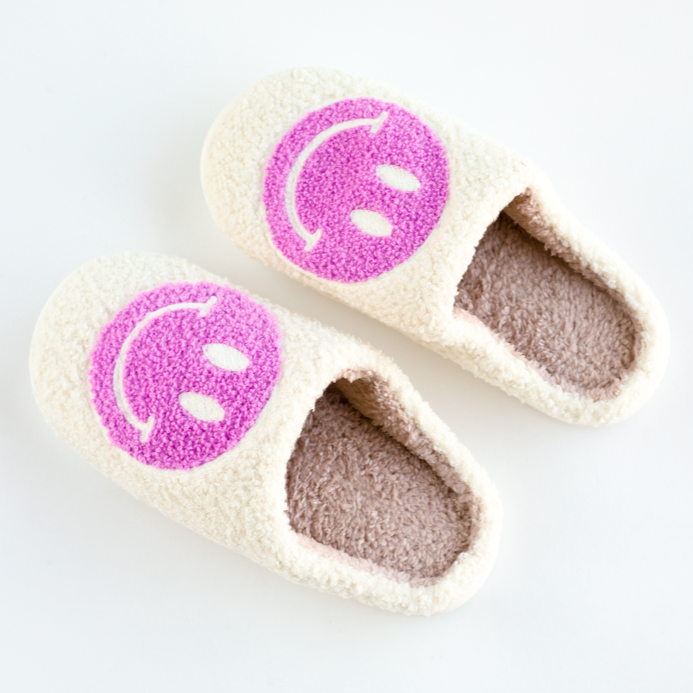 A pair of orchid smiley face slippers on a white background.