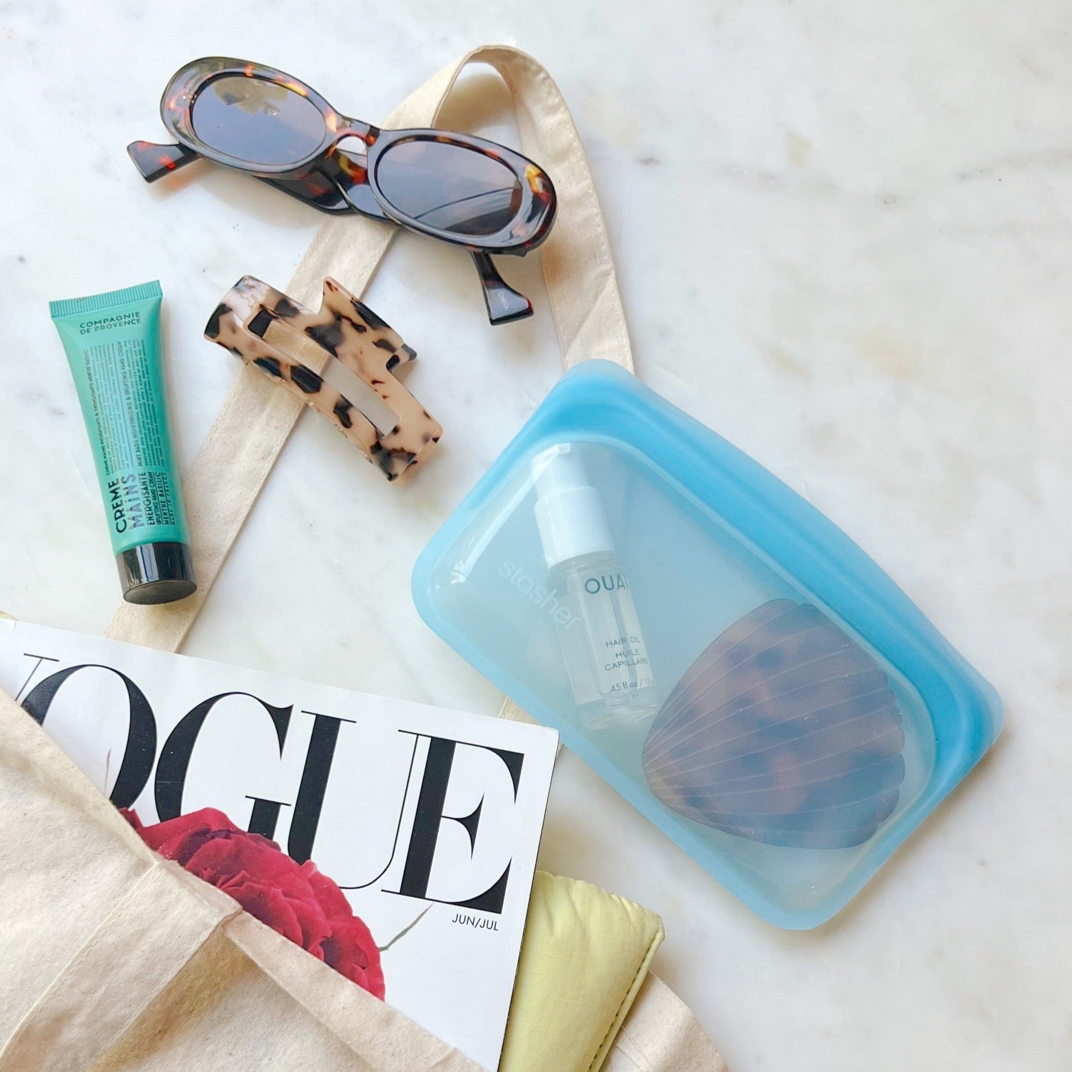Small blue bag filled with hair essentials spilling out from tote bag.