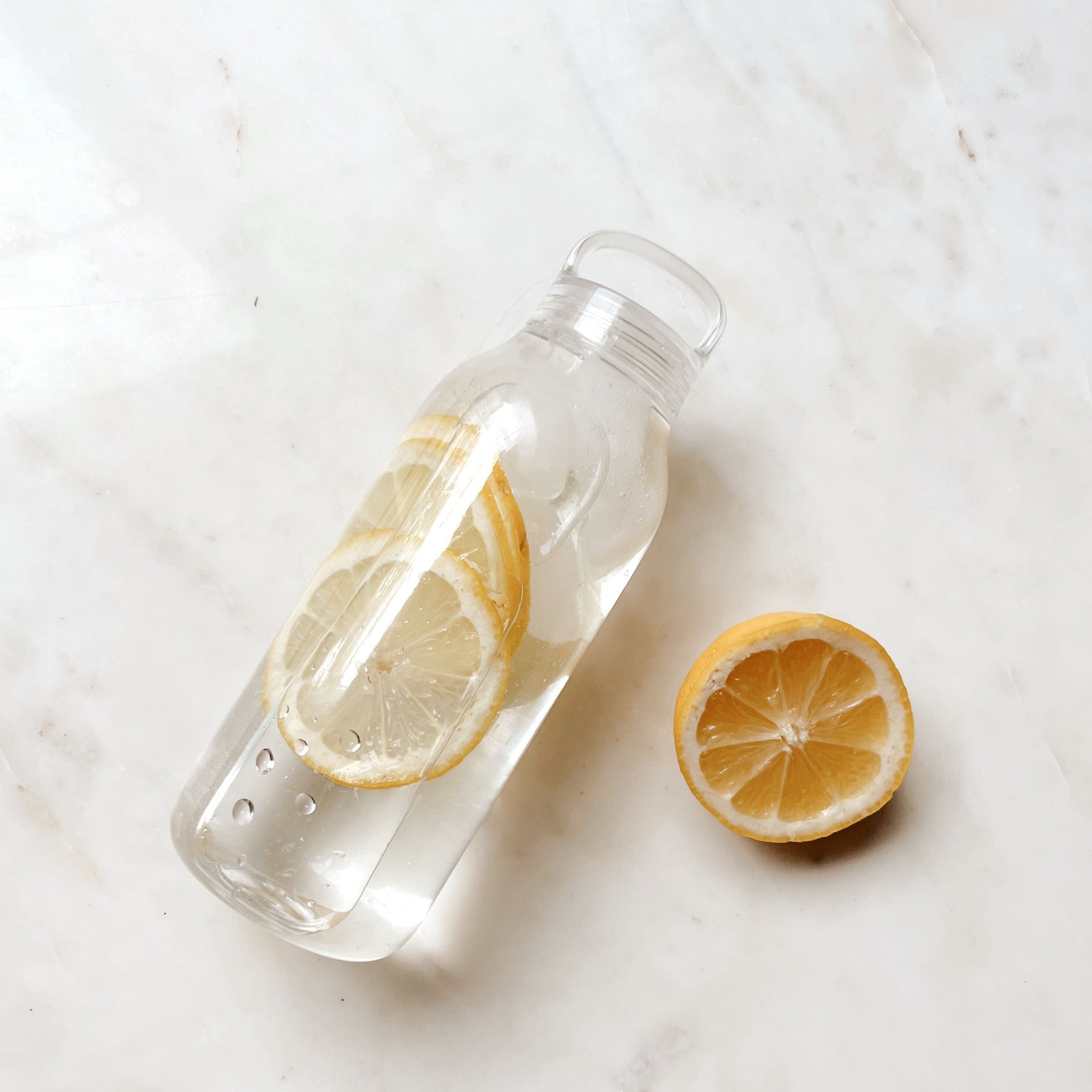 Clear water bottle filled with  slices of lemon  and water