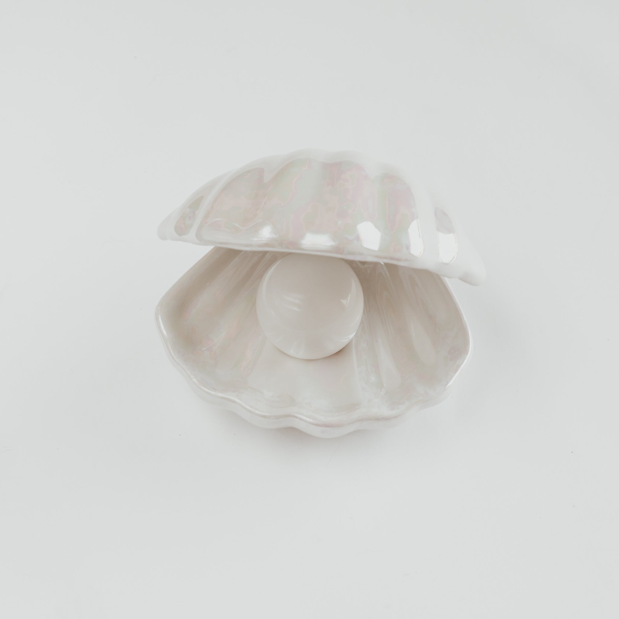 A white pearlescent ceramic shell tray with a pearl lamp inside against a white background