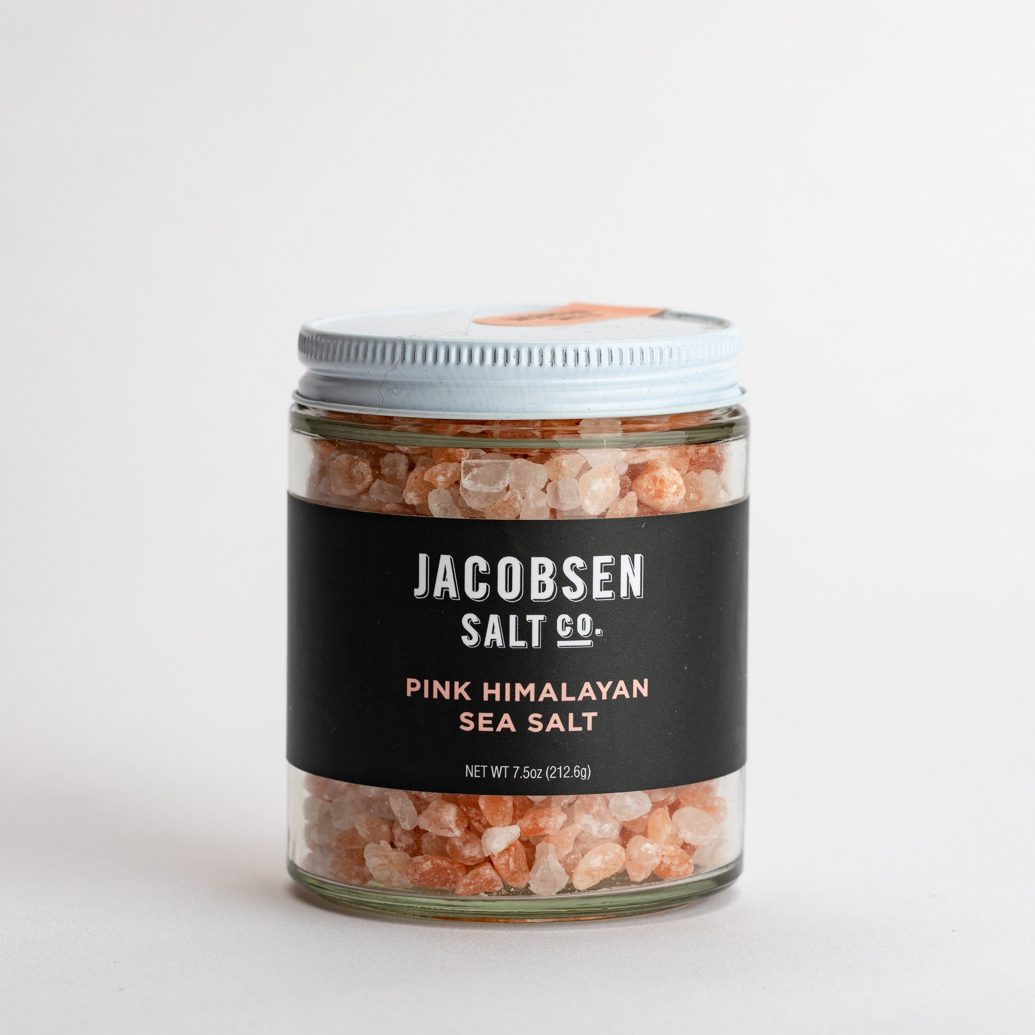 Glass jar filled with pink salt rocks, with a navy blue label.