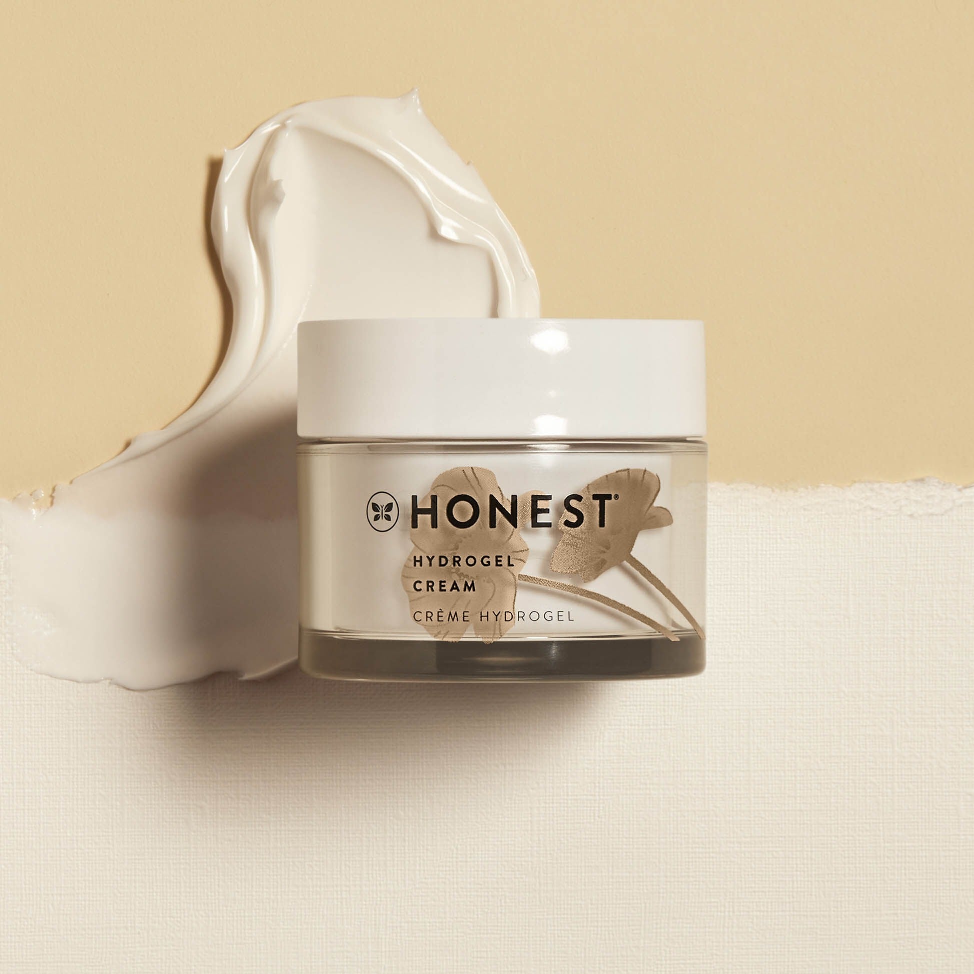 Short Jar of Honest Beauty Hydrogel Cream on tan background with cream swiped behind.
